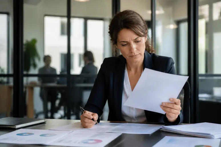 Une femme d'affaires française réfléchit à une demande de prêt bancaire dans son bureau.