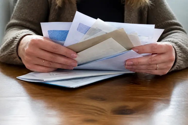 Mains tenant des documents administratifs et des enveloppes, symbolisant la gestion de son fichage FICP et les démarches de sortie.