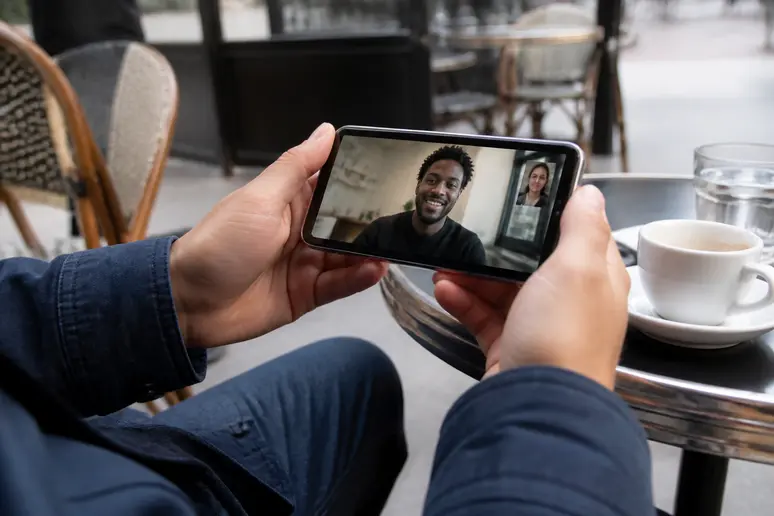 Utilisation de Jitsi Meet via smartphone dans un café français, illustrant la facilité d'accès et la mobilité.