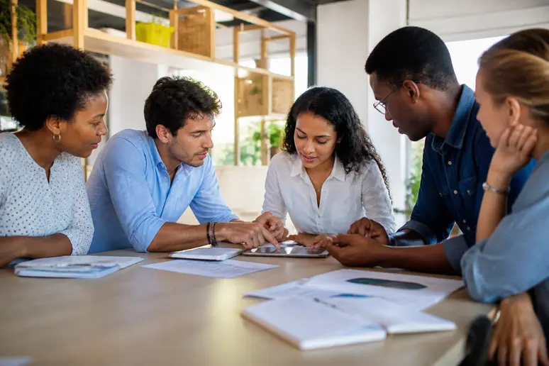 Des entrepreneurs guyanais échangent des idées autour d'une table dans un espace de co-working moderne, discutant de leur projet.