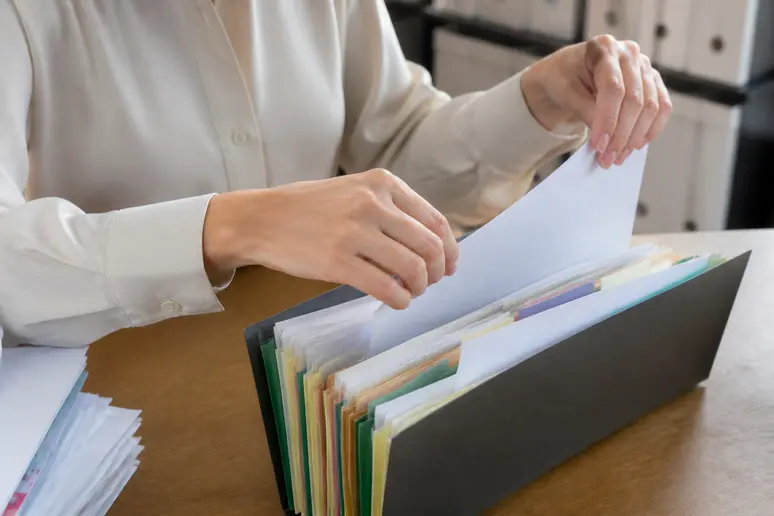 Mains triant et organisant des documents contractuels sur un bureau pour une gestion rigoureuse.