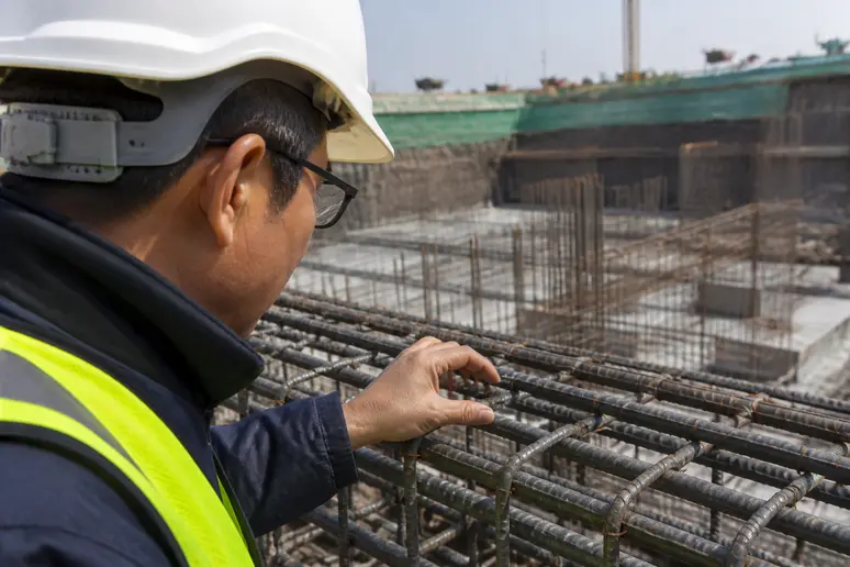 Ingénieur en gilet et casque de chantier inspectant des structures de béton armé