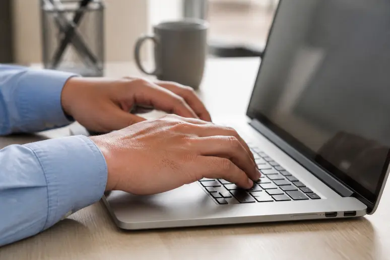 Mains tapant des données sur un logiciel de comptabilité moderne affiché sur un écran d'ordinateur.