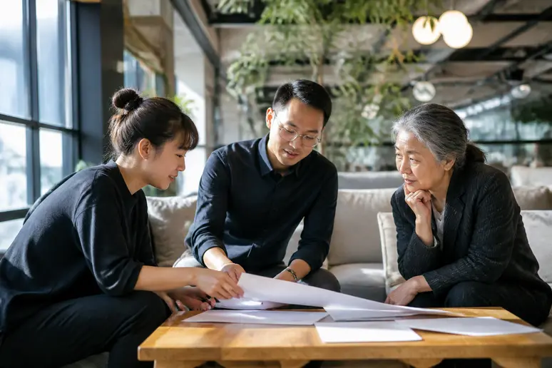 Trois professionnels diversifiés échangeant autour d'une table dans un espace de coworking moderne.