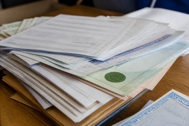 Tas de documents administratifs d'entreprise, formulaires et états financiers, organisés pour la conformité.