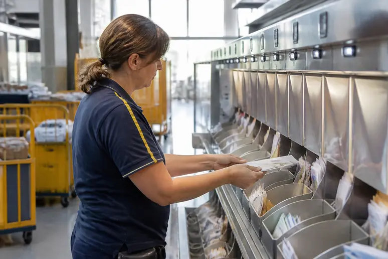 Un employé trie méticuleusement des lettres pour bien écrire une adresse enveloppe et assurer la distribution.