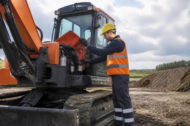 Salarié examinant un engin de chantier mis en location pour des travaux personnels.