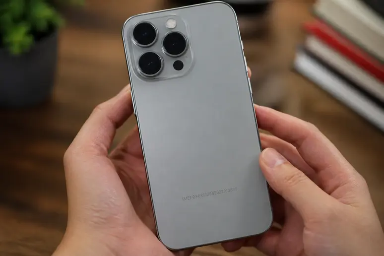 Mains manipulant un smartphone pour vérifier le numéro IMEI à quinze chiffres