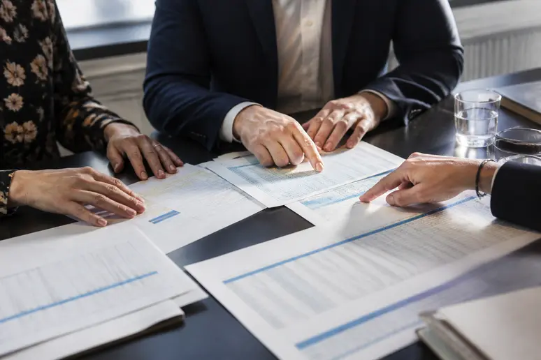 Mains comparant des grilles de salaires et des documents de convention collective sur une table